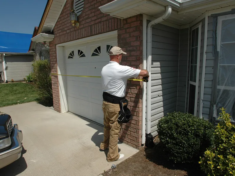 Insurance adjuster measuring a storm-damaged home