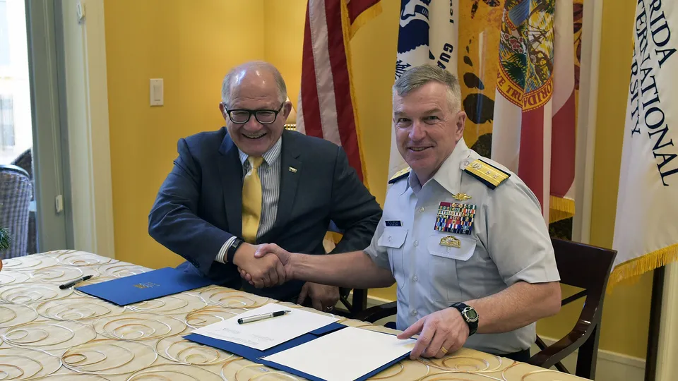 Two men shaking hands after signing an agreement